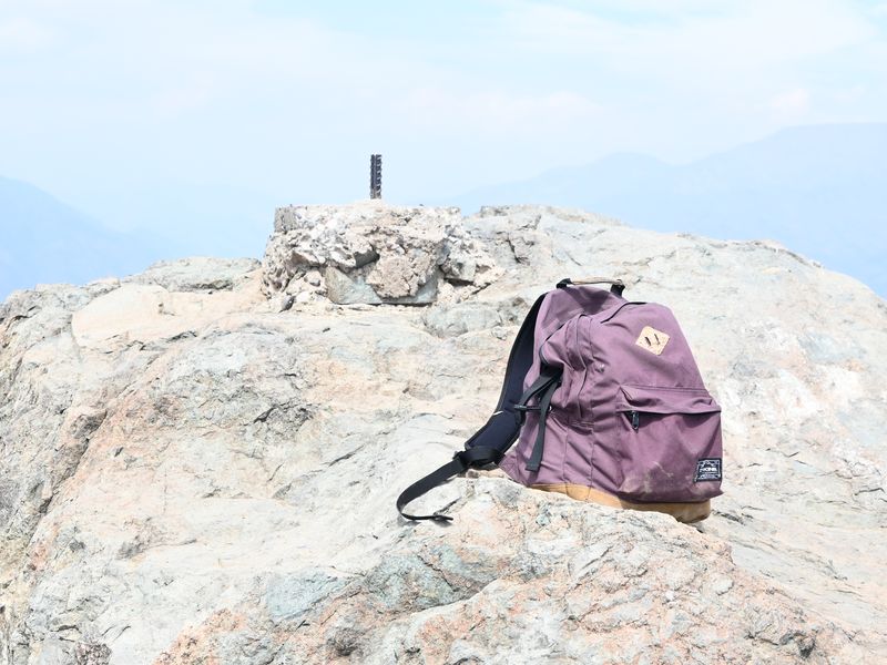 Ein Rucksack steht auf einem Felsen. Das Bild ist etwas überbelichtet.