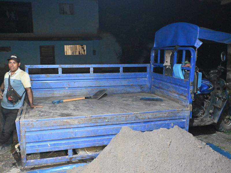 Der abgeladene Motorrad-LKW mit einem Haufen Sand davor.