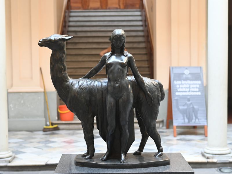 Eine lebensgroße Metall-Büste einer nackten Indígena vor einem Lama. Bild aus einer Kunsaustellung.