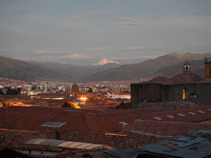 Cusco bei Sonnenuntergang mit einem großem schneebedecktem Berg im Hintergrund.