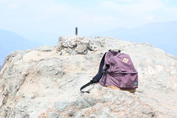 Ein Rucksack steht auf einem Felsen. Das Bild ist etwas überbelichtet.