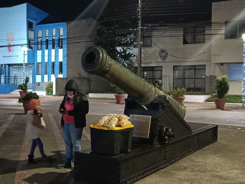 Eine alte Kanone die neben einem Christbaum, ein Händler verkauft hier auch Popcorn und hat seine Ware unter der Kanone platziert