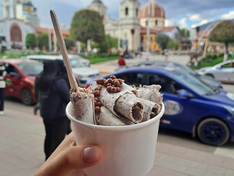 Ein Rolled Ice mit Löffel vor einer Kirche am Hauptlatz Huancayos.
