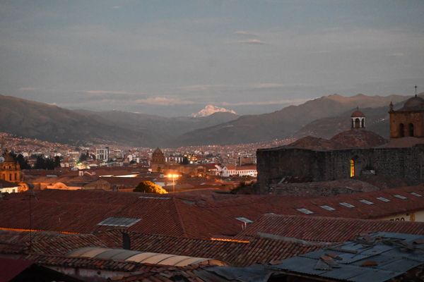 Cusco bei Sonnenuntergang mit einem großem schneebedecktem Berg im Hintergrund.