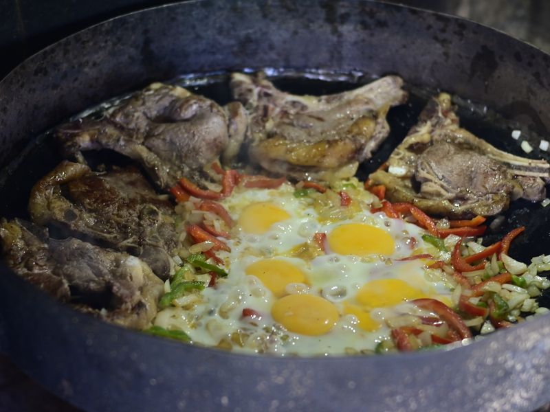 Steak, Ei und Gemüse werden noch über dem offenen Feuer gekocht.